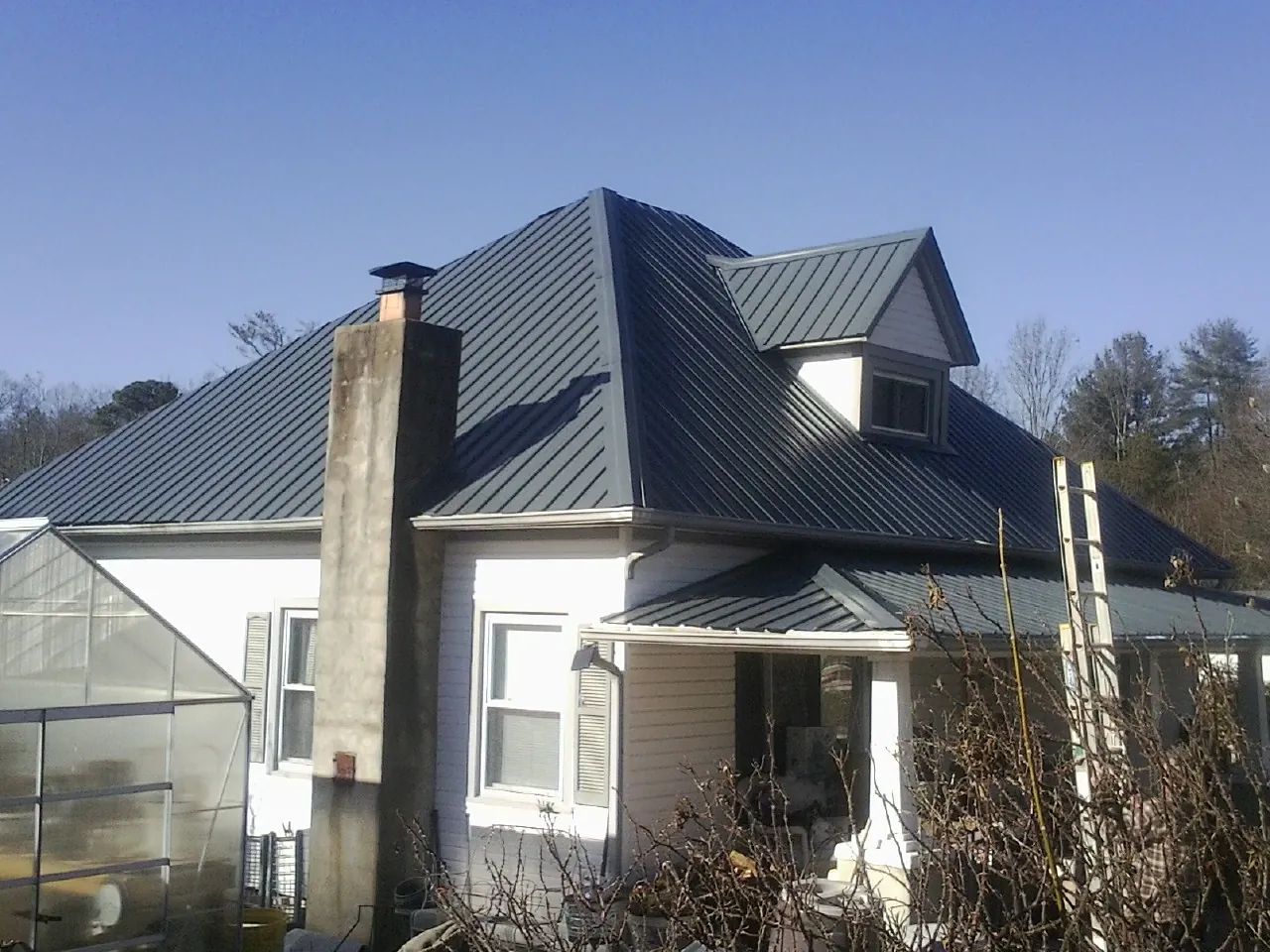 Dark blue standing seam metal roof on a white farmhouse with dormer — Slate & Tile Roof Repair by Roofing Brothers in Lake Winola
