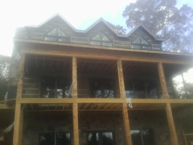 Dormers and porch framing on a large log home under construction — Roof Coating work by our crew in Lake Winola