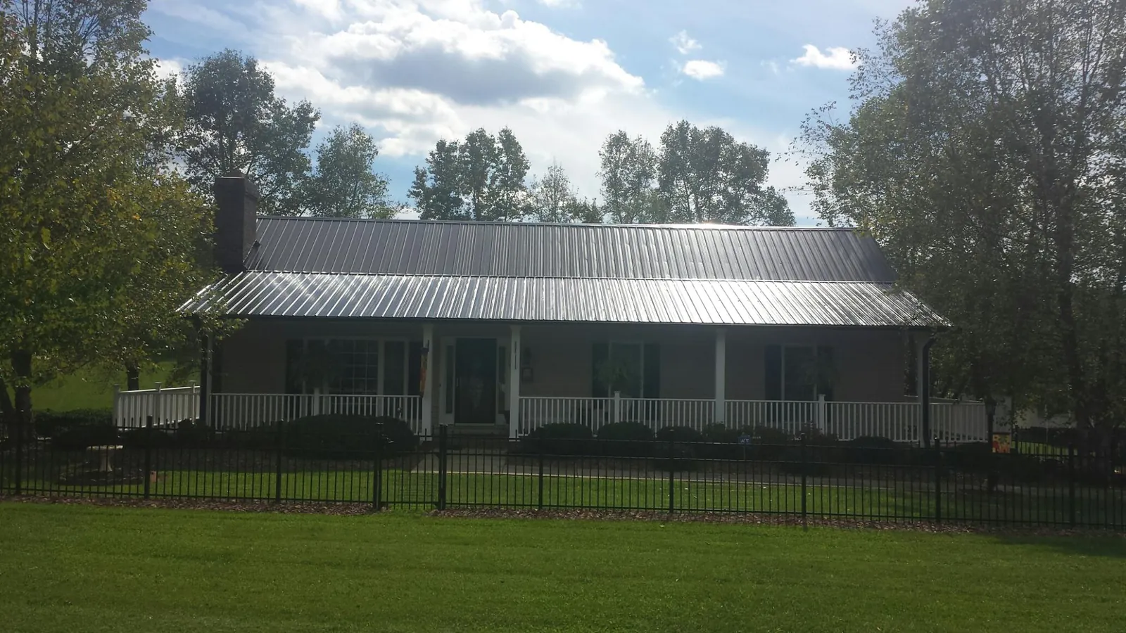 Gray metal roof on a brick ranch with a full width front porch — Gutter Guard Installation work by our crew in Lake Winola