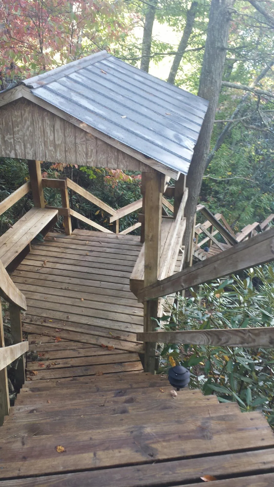 Metal roofed shelter over wooden steps on a wooded walkway — Skylight Repair & Installation work by our crew in Lake Winola