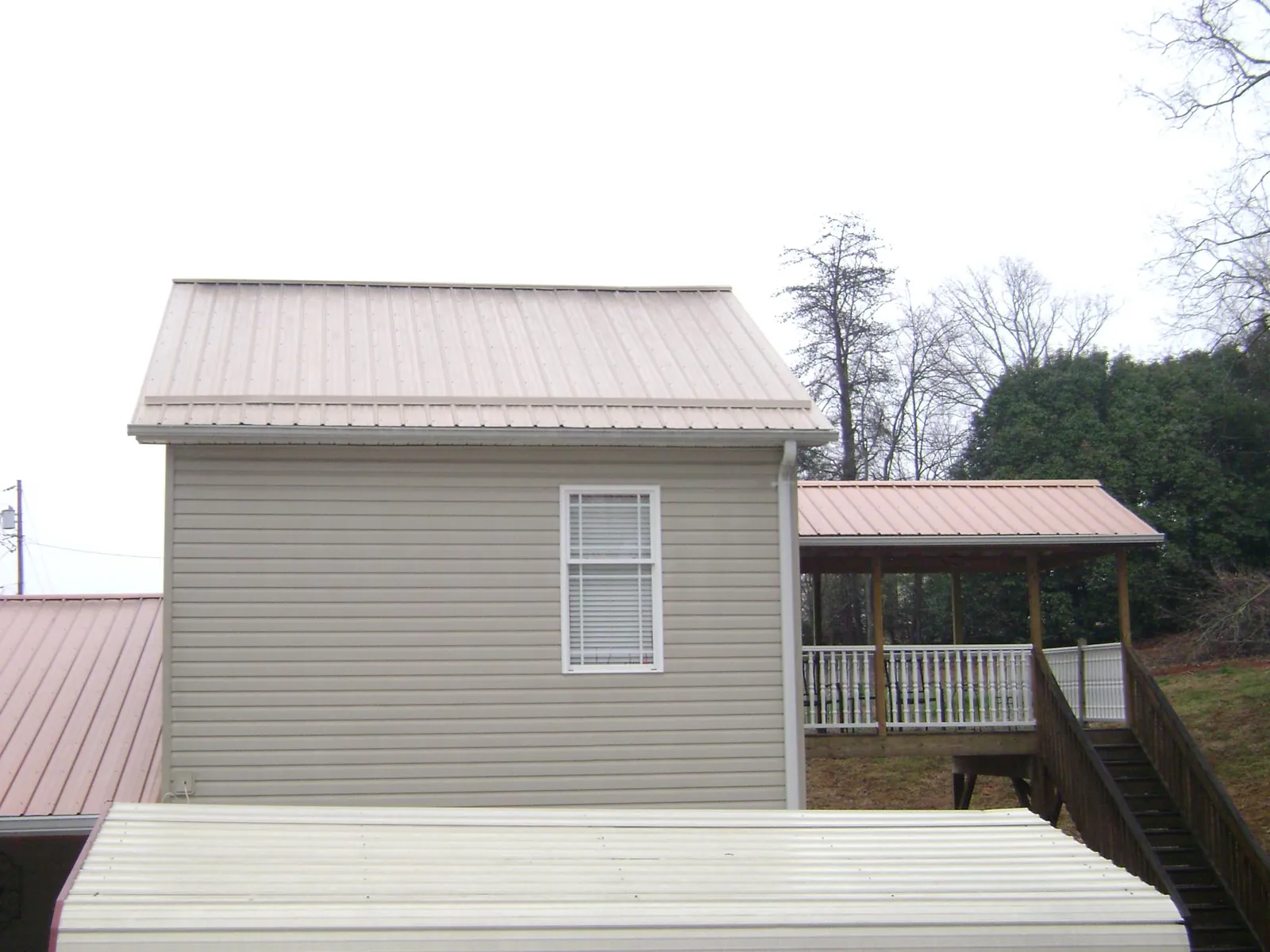Tan metal roofs on a two story addition and attached porch, from a Roof Replacement job in Lake Winola