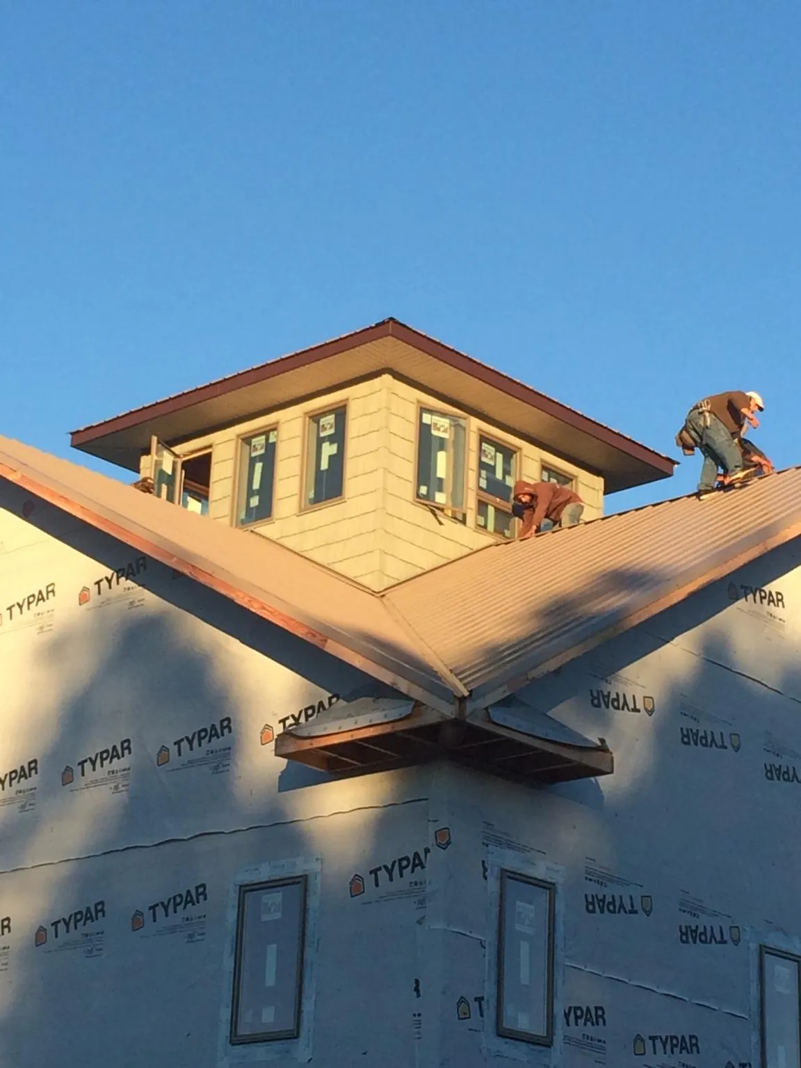 Roofers working around a rooftop cupola on a new metal roof at sunset — Roof Waterproofing in Lake Winola by Roofing Brothers